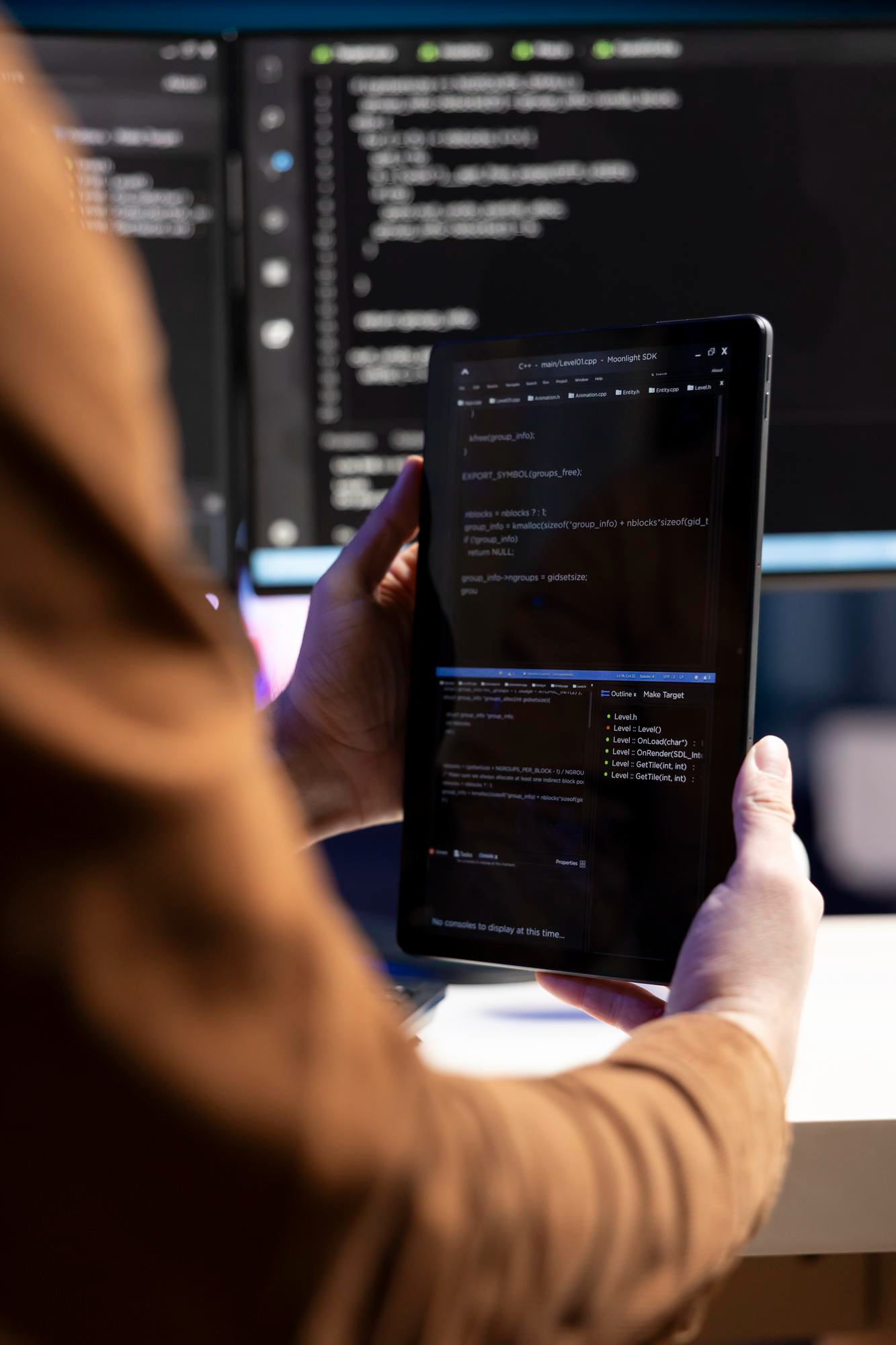 Developer reviewing code on a tablet in front of a monitor